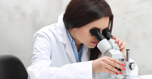 Mujer en el laboratorio mirando por microscopio