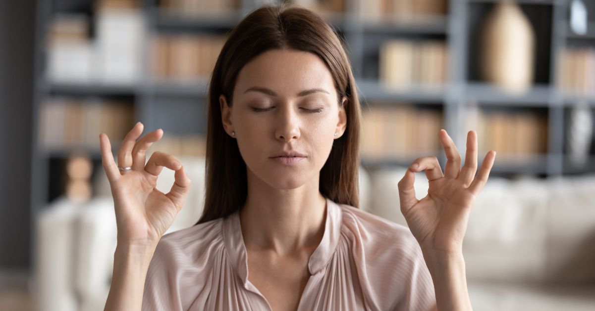 Mujer con los ojos cerrados y en pose de relajación para combatir y aliviar el estrés emocional