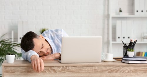 Homem cansado recostado sobre uma mesa de trabalho devido à falta de magnésio