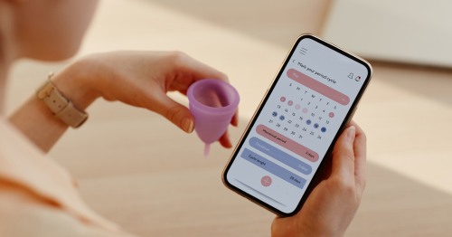 Mulher com calendário de ovulação e copo menstrual.