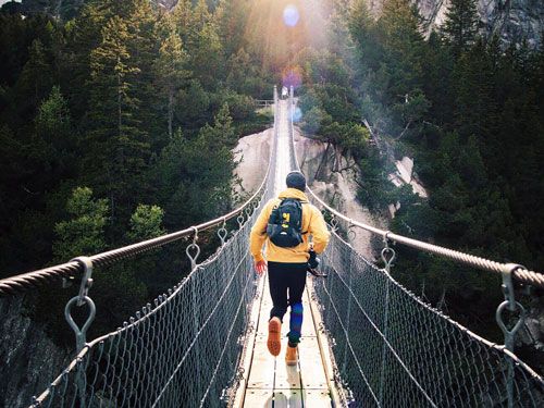 Un chico corriendo por un puente en la naturaleza