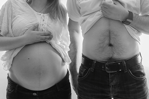 Mujer embarazada y su pareja mostrando la barriga