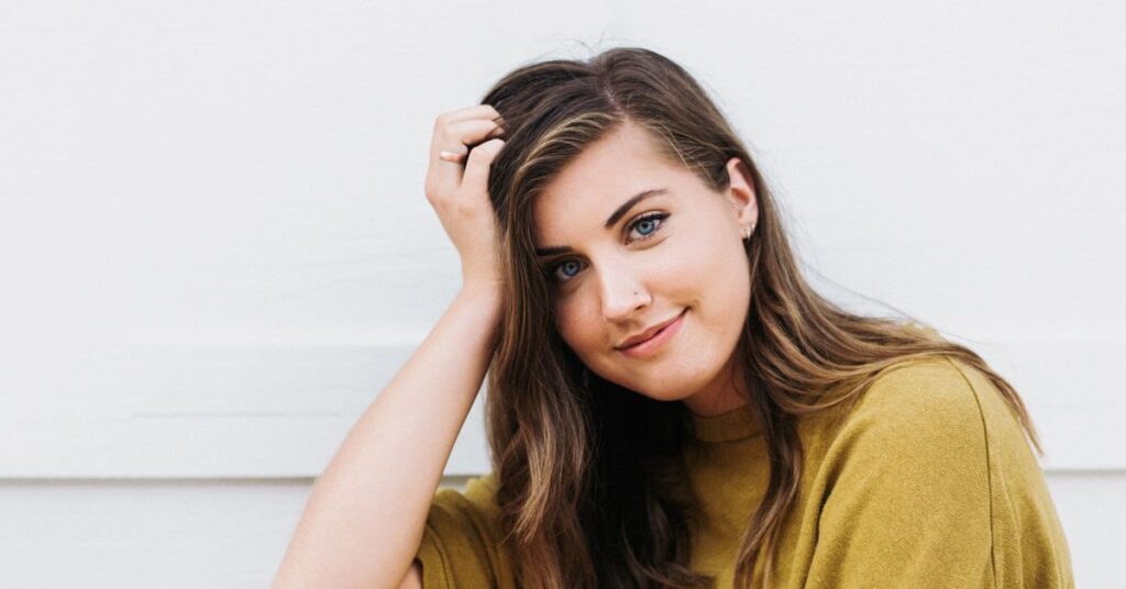 Mujer sonriente con la mano en la cabeza