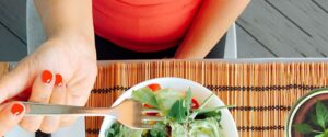 Mujer comiendo ensalada, un buen alimento para evitar el vientre hinchado en la menopausia