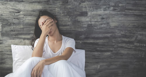 Mujer en la menopausia acostada en cama manifestando cansancio