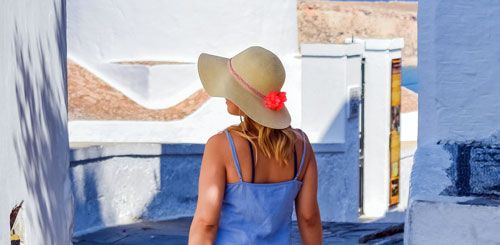 Mujer de espaldas con sombrero para protegerse del sol y el envejecimiento prematuro de la piel