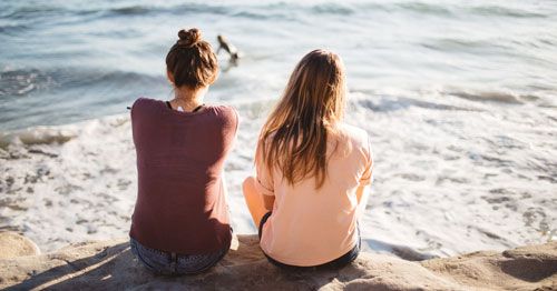Dos chicas sentadas en la playa.