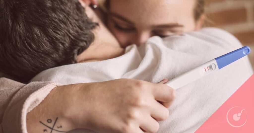 Pareja abrazándose con test de embarazo