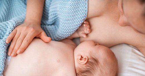 Mujer acostada con su bebÃ© para favorecer un buen agarren en la lactancia.