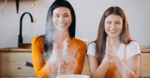 Madre e hija en la cocina jugando con harina