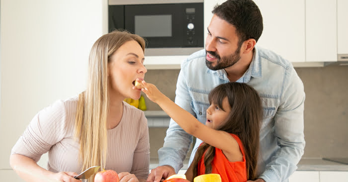 Imagen de una familia en la que la niña da de comer a su madre