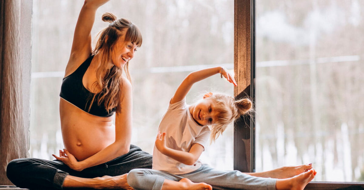 Mujer embarazada haciendo yoga con su hija