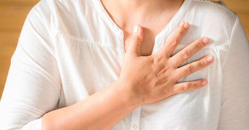mujer con mano en el pecho y colesterol alto