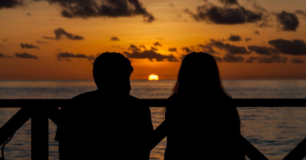 Pareja mirando la puesta de sol en la playa