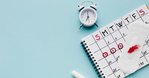 Imagen de un calendario, un reloj y productos femeninos para la menstruación.