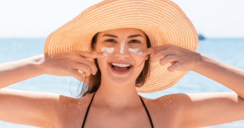 Chica aplicando crema solar en la piel