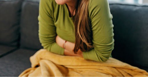 Mujer sentada en un sofá con síntomas de colon irritable y ansiedad