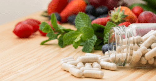 Frutas, verduras y bote de cápsulas con pastillas naturales para la menopausia