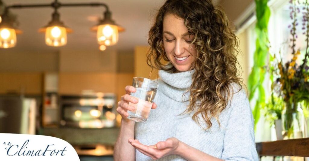Mujer con un vaso tomando pastillas naturales para la menopausia