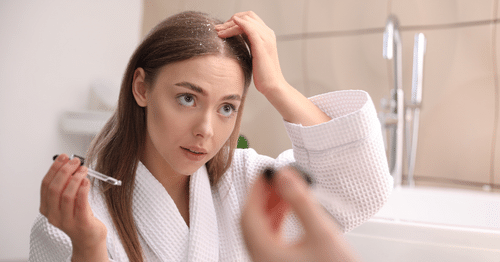 Mujer rubia aplicándose tratamientos naturales para la dermatitis en el cuero cabelludo