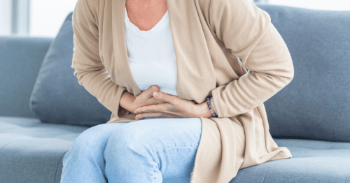 Mujer sentada en el sofá con dolor en el intestino