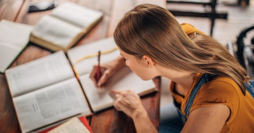 Imagen de una mujer escribiendo y estudiando 