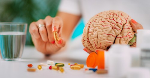 Mujer sosteniendo una réplica de un cerebro y una cápsula de vitaminas para la memoria