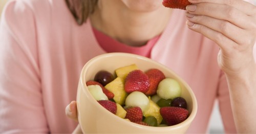 Primer plano de una mujer sosteniendo un bowl de frutas antioxidantes