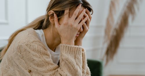 Mujer en menopausia con niebla mental, con las manos sobre el rostro en expresión de cansancio