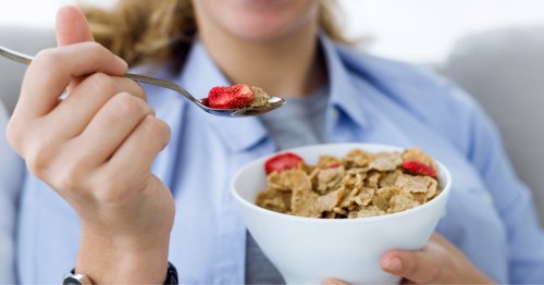 Mujer comiendo cereales con frutas, un plato rico en antioxidantes naturales