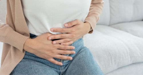 Mujer sentada con manos en la tripa 