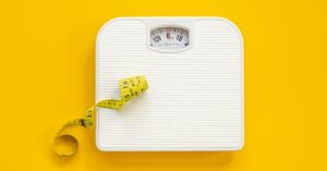 Cabecera del artículo sobre si AnimaFort MULTI engorda, con báscula y cinta métrica sobre fondo naranja