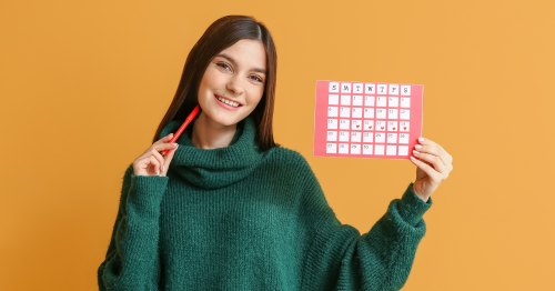 Mujer joven sonriente con un calendario menstrual