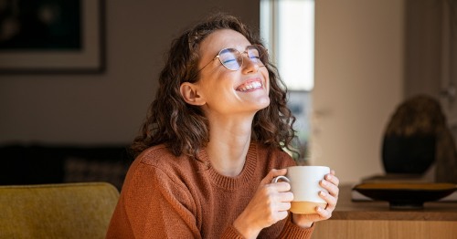 Mujer joven sonriendo con una taza en la mano