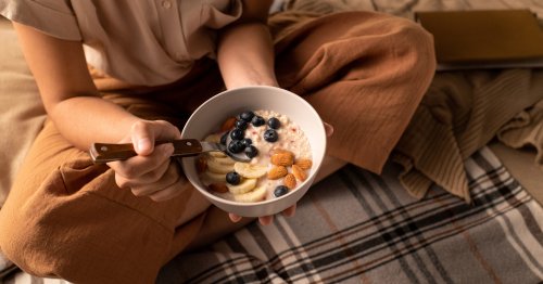 Mujer desayunando un bowl de avena con frutas bajas en FODMAP, alimentos buenos para el colon irritable