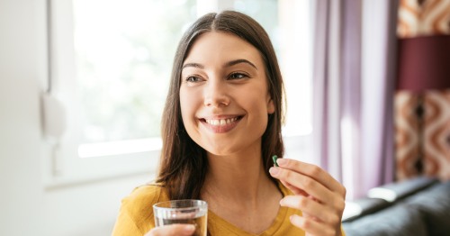 Mujer sonriendo sosteniendo un suplemento para aliviar el estrés emocional