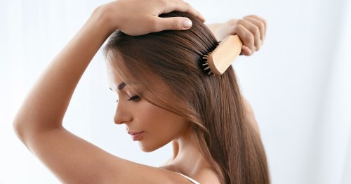 Mujer cepillándose el cabello con peine de bambú