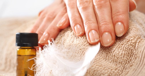 Uñas sanas de mujer junto a un bote de biotina