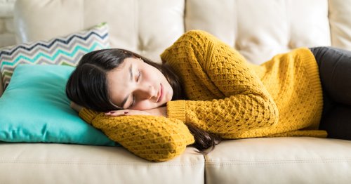 Mujer con cansancio antes de la regla durmiendo en el sofá