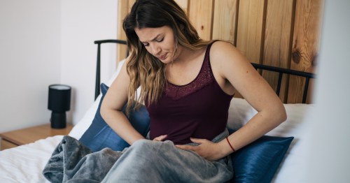 Mujer con SOP y dolor menstrual sentada en la cama