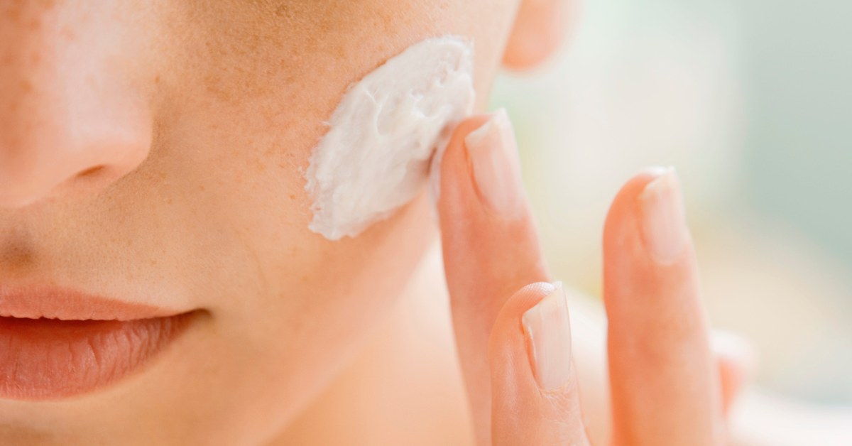 Mujer aplicando crema hidratante en el rostro